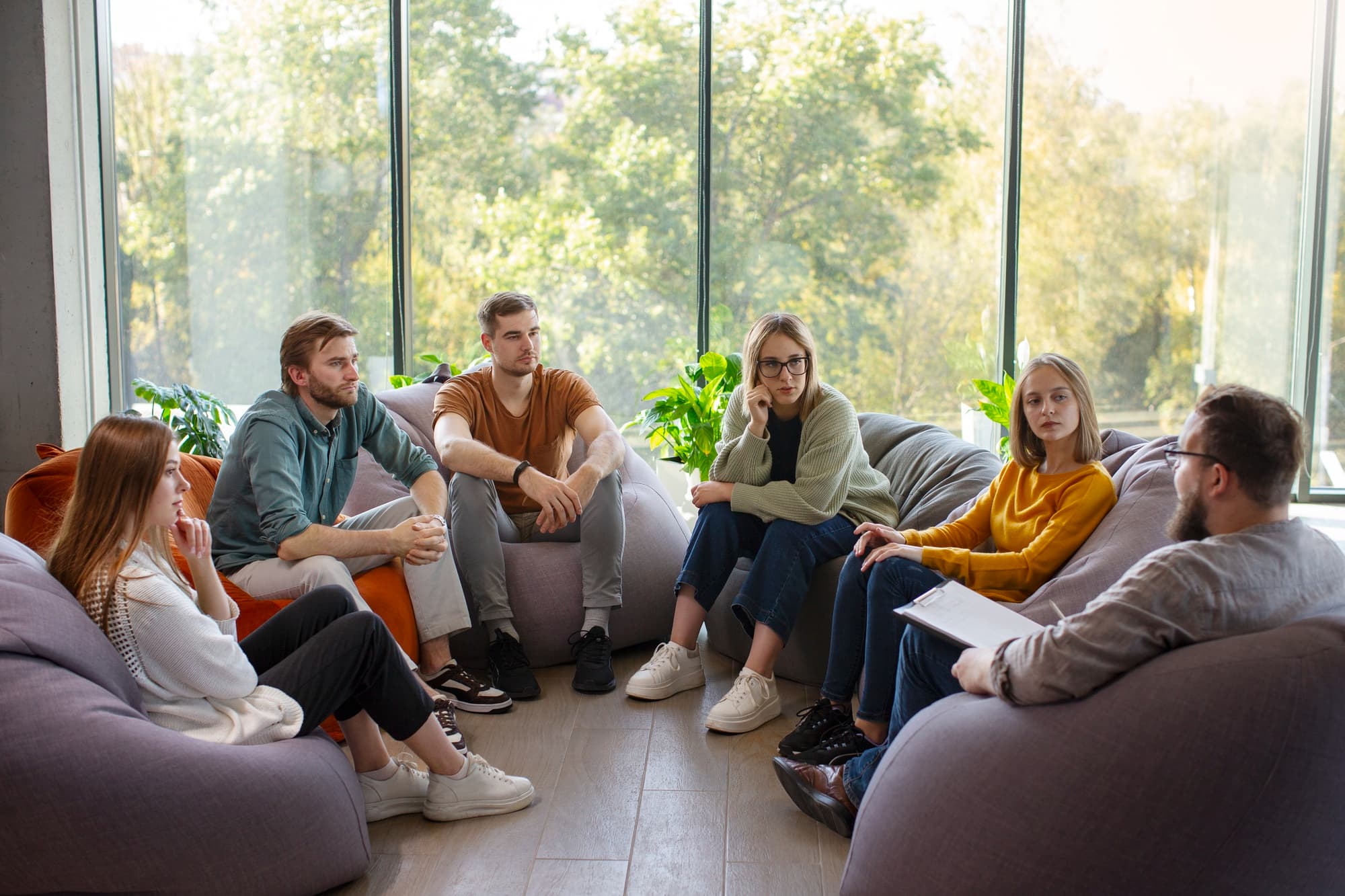 A group of corporate employees engaging in a group therapy session aimed at promoting mental health at work.