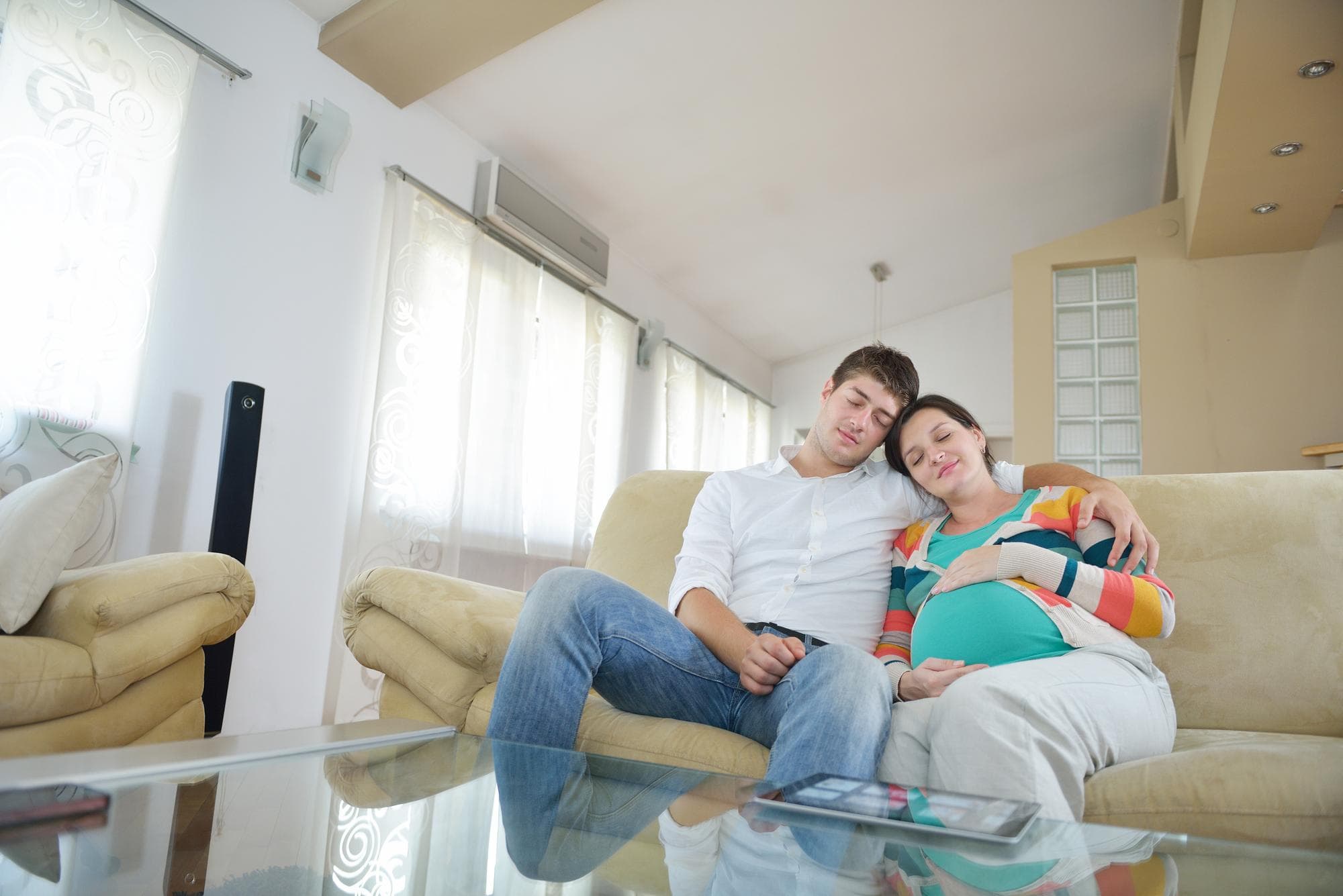 A pregnant woman and her husband are relaxing in a chair to deal with symptoms of postpartum blues.