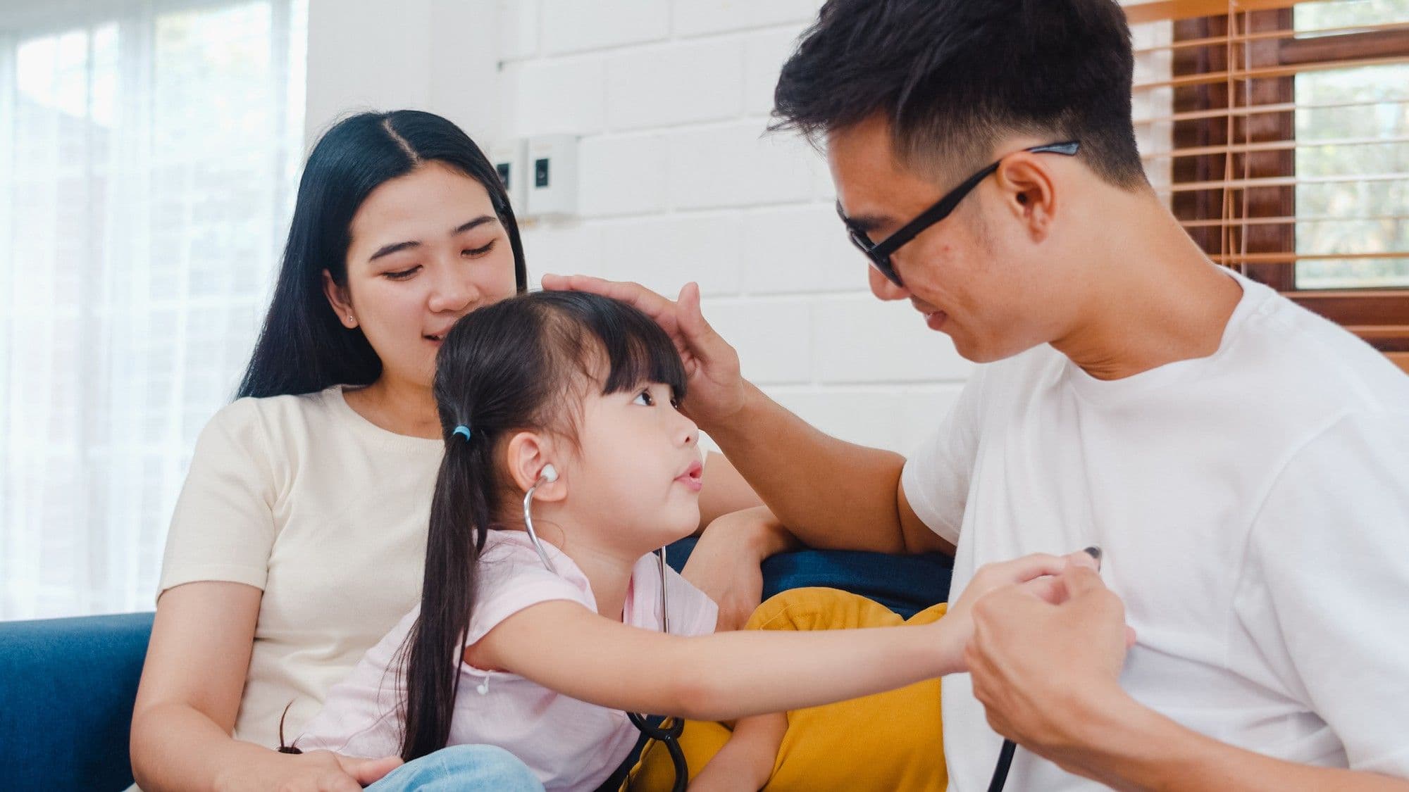 Parents and a child sitting on a couch and applying therapeutic skills learned during premarital counselling in Singapore.