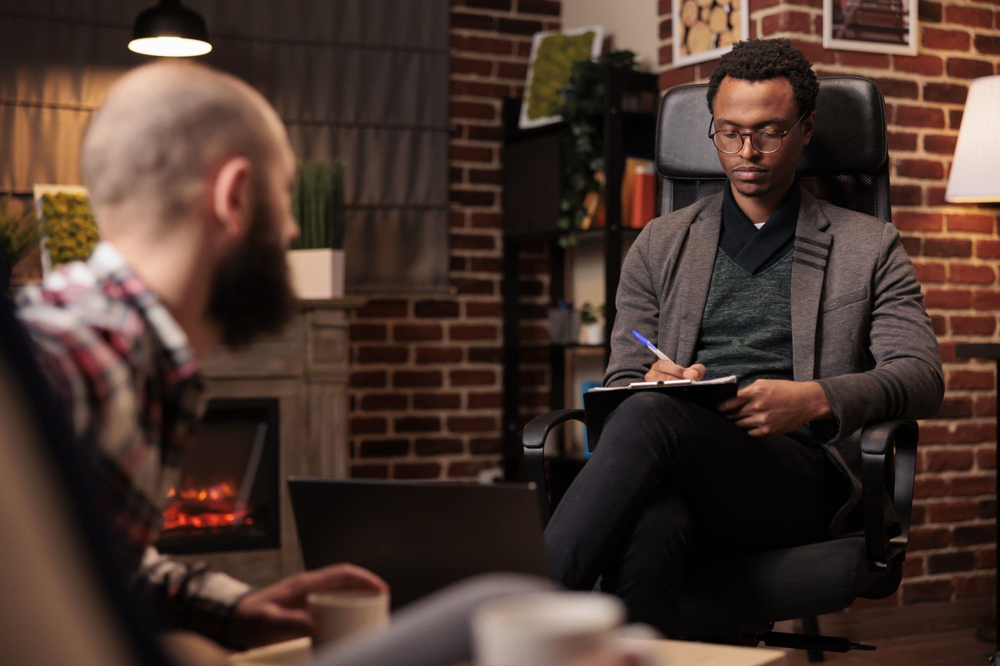 A therapist taking notes while the client talks about personal development during a therapy session.